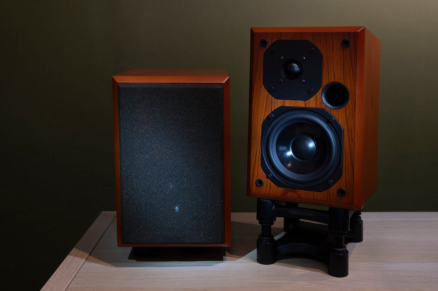 Two wooden speakers on a wooden surface with a dark background